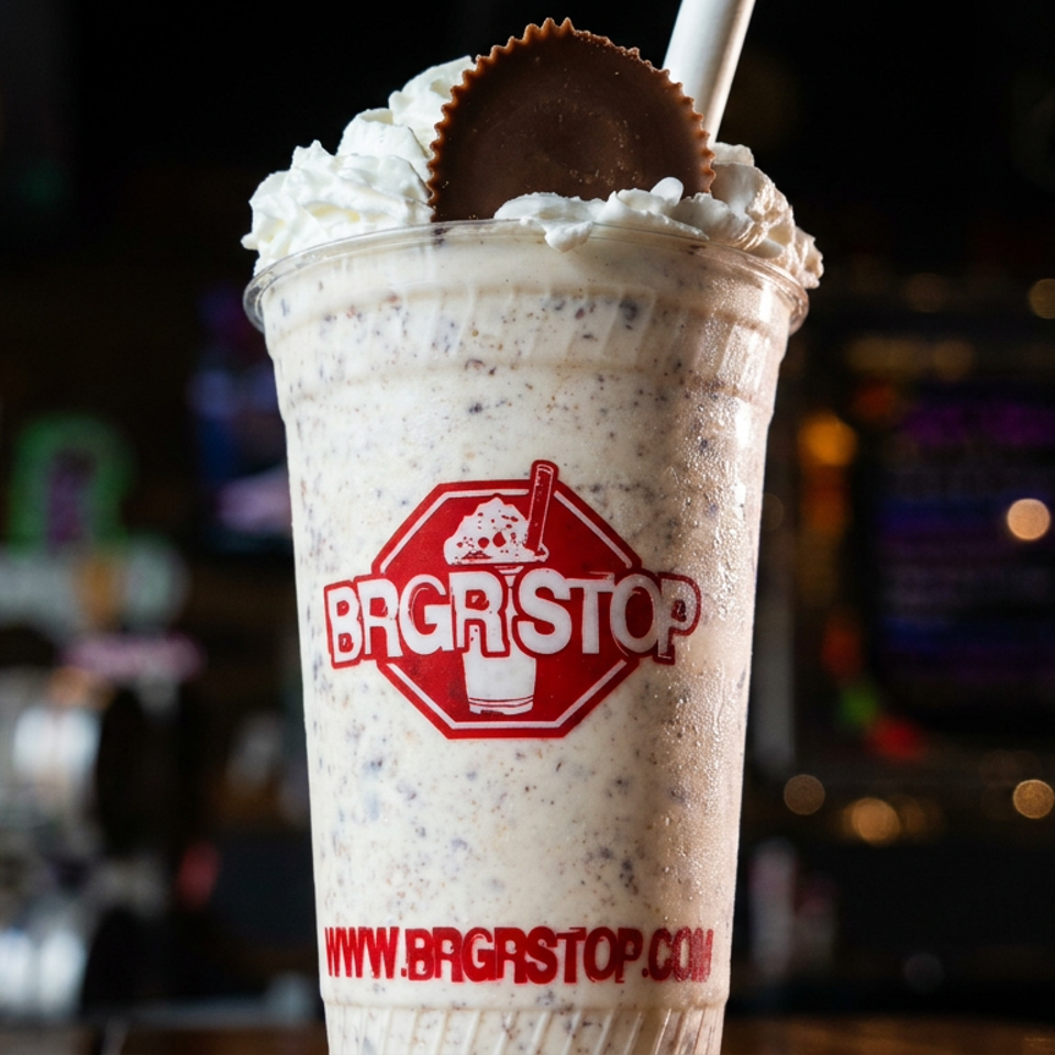 Cookies-and-cream milkshake topped with whipped cream and a chocolate peanut butter cup in a branded BRGRSTOP cup.